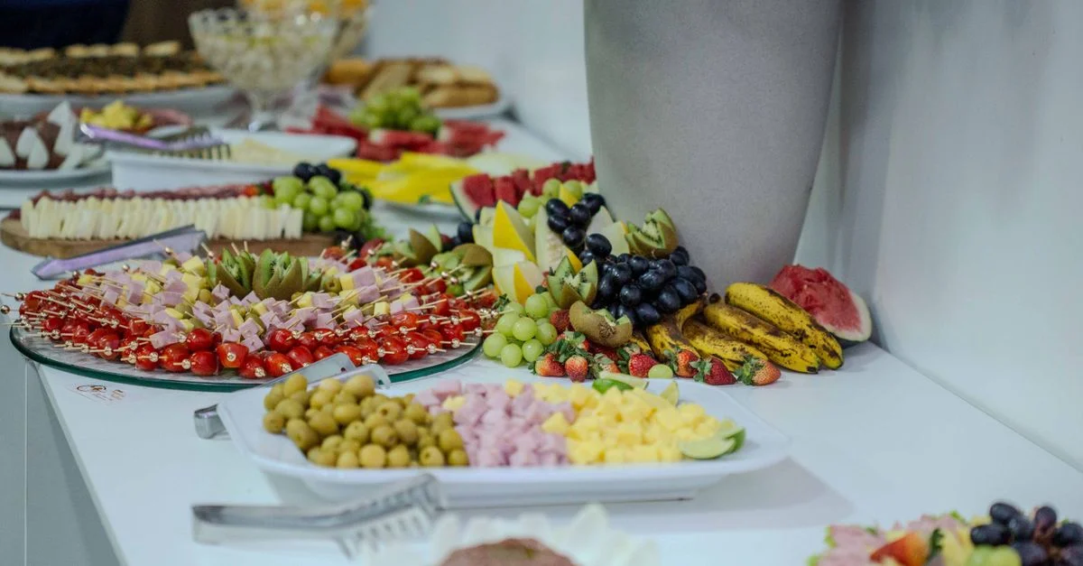 Assortiment vibrant de fruits et apéritifs magnifiquement disposés sur une table de buffet à l'intérieur.