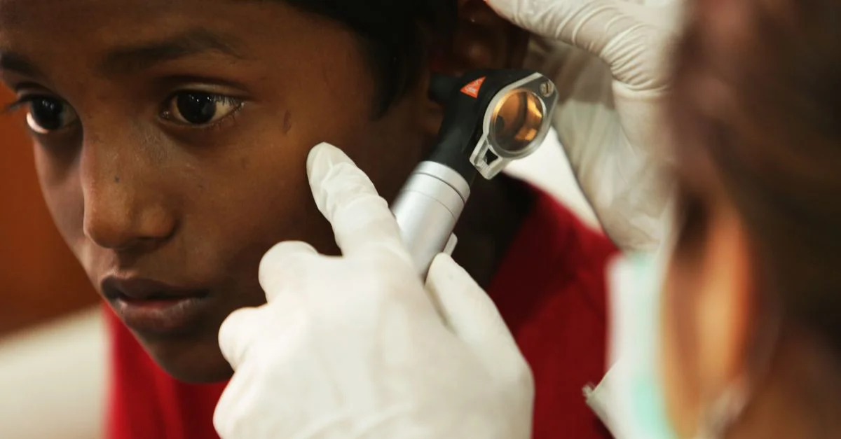 Un jeune garçon subit un examen de routine de l'oreille par un professionnel de la santé utilisant un otoscope.