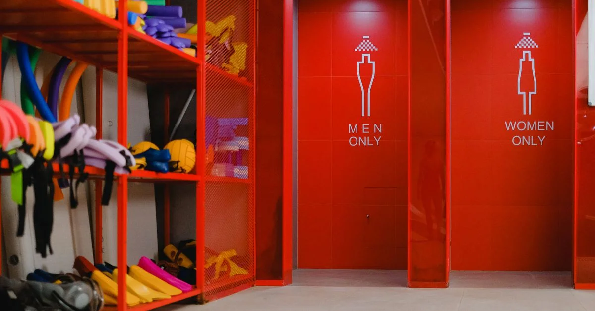 Équipement de piscine coloré en stockage à côté de douches spécifiques au genre avec une décoration rouge vibrante.