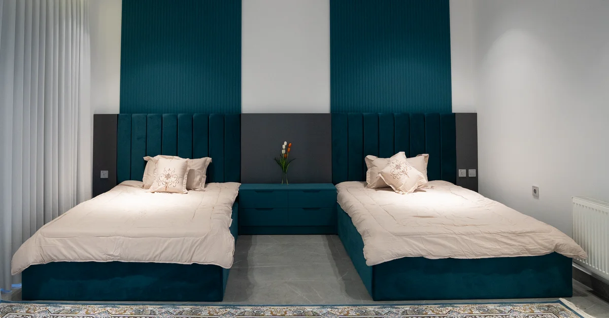 Chambre twin moderne avec des accents bleu-vert, têtes de lit élégantes et décoration cosy.