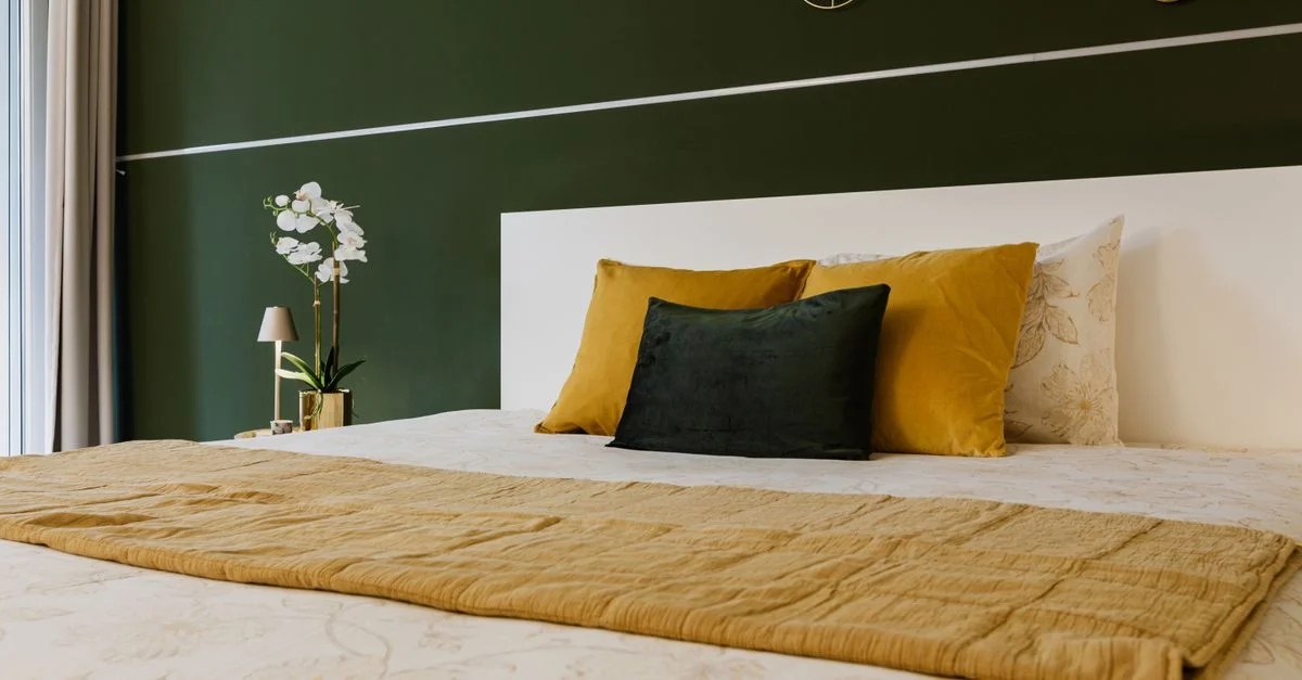 Chambre élégante au design soigné, avec murs verts, coussins jaunes et décorations murales géométriques. Idéale pour une déco moderne et inspirante.