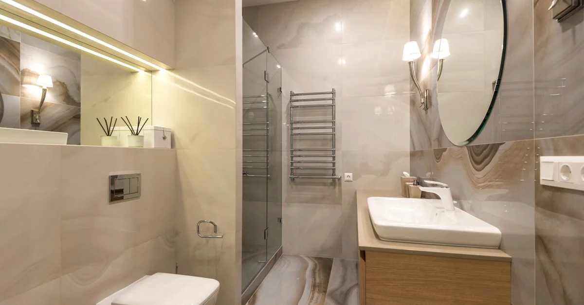 Salle de bain élégante avec carreaux en marbre, grand miroir et équipements modernes.