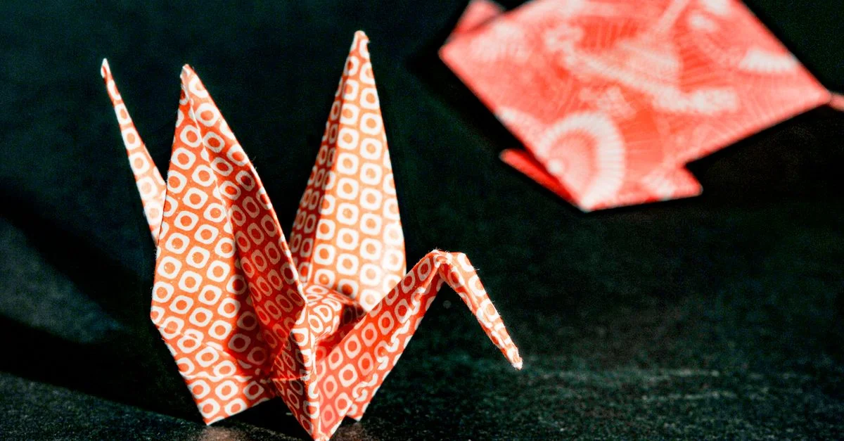 Gros plan d'une grue origami rouge avec des motifs géométriques, mettant en valeur un travail artisanal délicat.