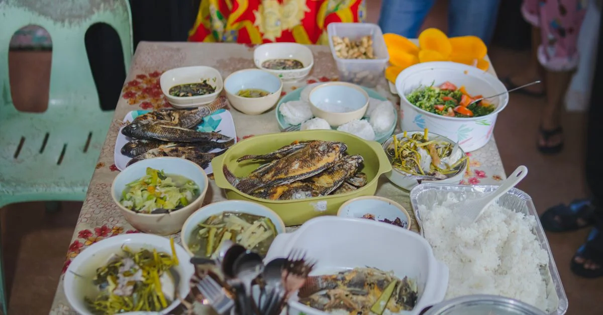 Un éventail vibrant de plats philippins traditionnels, y compris du poisson frit et divers plats d'accompagnement sur une table.